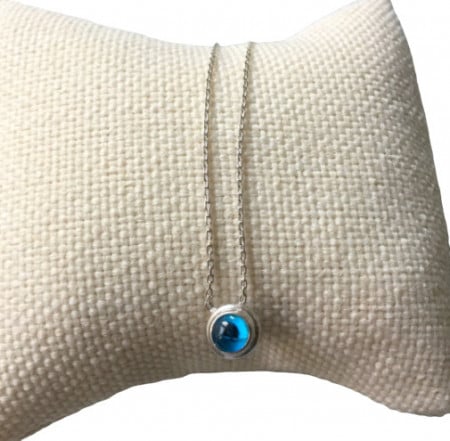 Sterling silver necklace featuring a round blue beaded evil eye pendant, minimalist design.