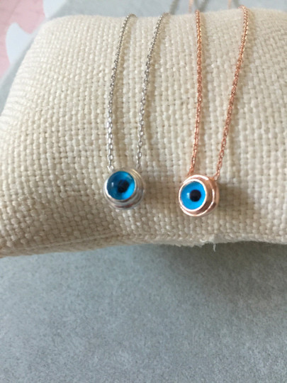 Sterling silver necklace featuring a round blue beaded evil eye pendant, minimalist design.