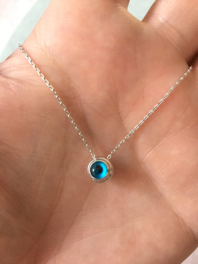 Sterling silver necklace featuring a round blue beaded evil eye pendant, minimalist design.