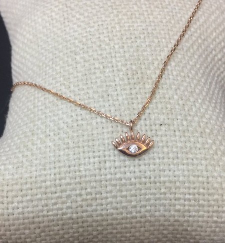 Close-up image of a gold-plated sterling silver evil eye necklace with a cubic zirconia centerpiece, hanging on a delicate chain.