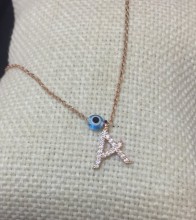 Close-up image of a personalized initial "A" necklace with cubic zirconia detailing and an evil eye charm, crafted in 18K gold-plated sterling silver.