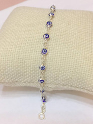 Sterling silver mini evil eye bracelet with purple bead charms and protective evil eye motifs for a chic and meaningful accessory.
