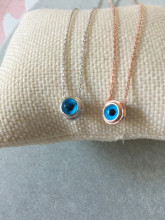 Sterling silver necklace featuring a round blue beaded evil eye pendant, minimalist design.