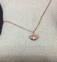 Close-up image of a gold-plated sterling silver evil eye necklace with a cubic zirconia centerpiece, hanging on a delicate chain.