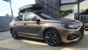 Hyundai i30 with Menabo Tema aluminium roof bars and a Menabo Marathon Dark 400 roof box