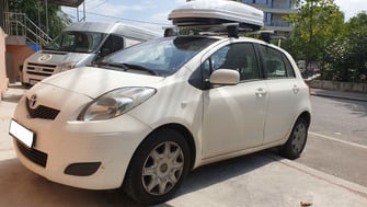 Toyota Yaris with Menabo Delta Silver roof bars, a Menabo Mania roof box and a Menabo Stand Up bike rack