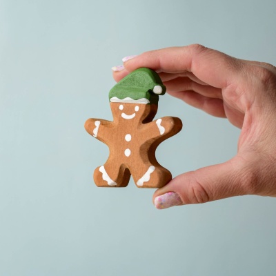 Close-up of a hand holding the Gingerbread Cookie Boy figurine, showcasing its hand-painted details.