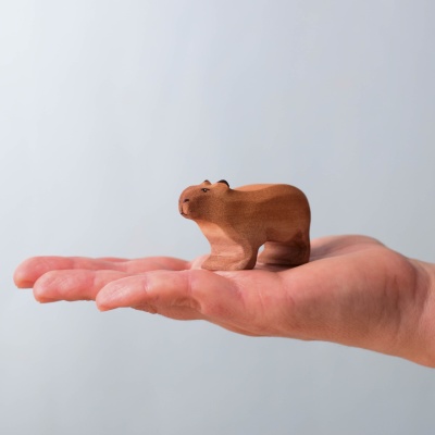 Small wooden capybara resting in a hand, showing its size.