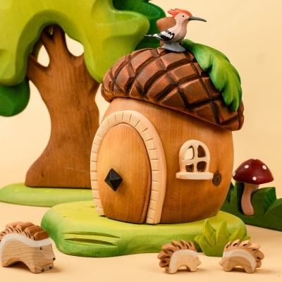 Child hand holding the curved brown wooden roof piece of the acorn house toy