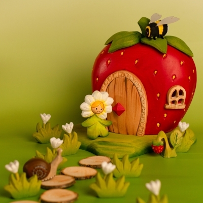 BumbuToys garden scene featuring the Flower Child Daisy standing next to a red wooden Strawberry House and a snail.