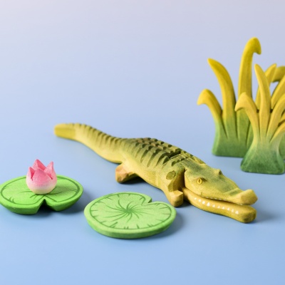 Crocodile toy next to lily pads in a nature-themed play scene