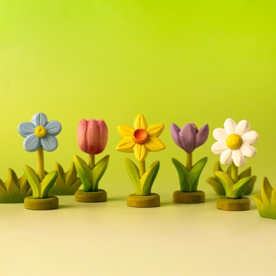 Colorful row of wooden spring flowers including a blue daisy pink tulip and yellow daffodil
