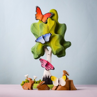 Wooden pink butterfly on a tree display with animals and colorful butterflies.