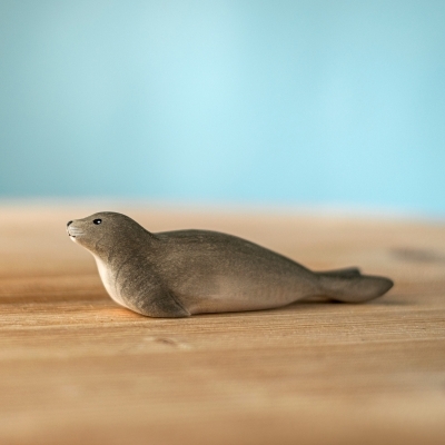 Back view of a wooden seal toy showing smooth carved tail details and natural wood texture.