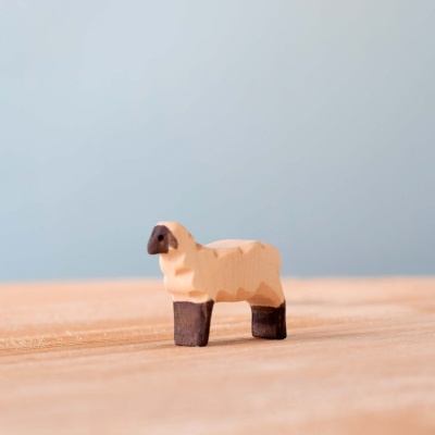 Image of a hand-carved wooden lamb figurine in a running pose, with its head up and mouth open.