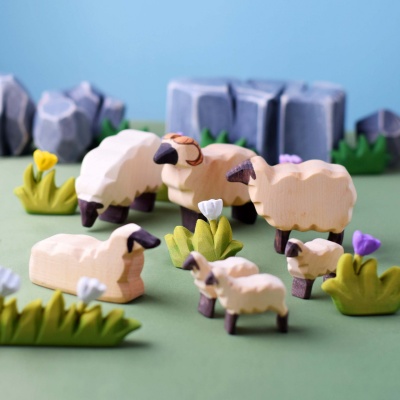 The lamb figurine incorporated into a nature-themed play scene with wooden trees and grass.