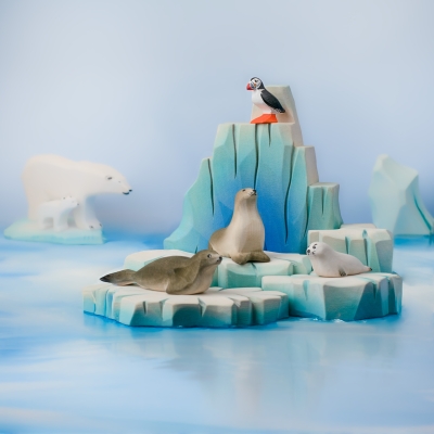 Complete Arctic small world scene with wooden puffin, seals, and polar bears on a blue surface.