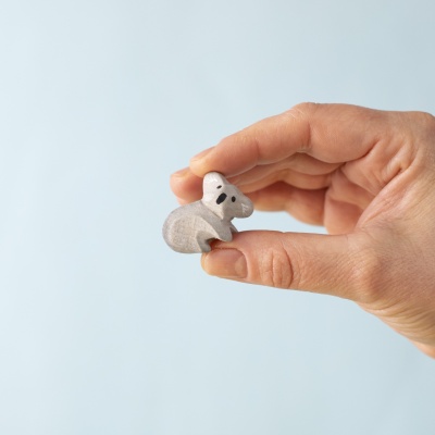 Small koala cub figure held between fingers, showing its compact size.