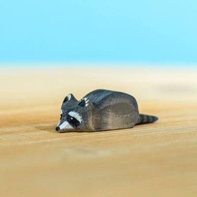 Single handcrafted wooden raccoon figure lying down by Bumbu Toys