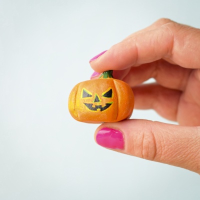 Small wooden Halloween pumpkin held in hand.