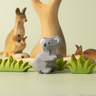 Koala bear placed among kangaroos and plants in an Australian nature scene.