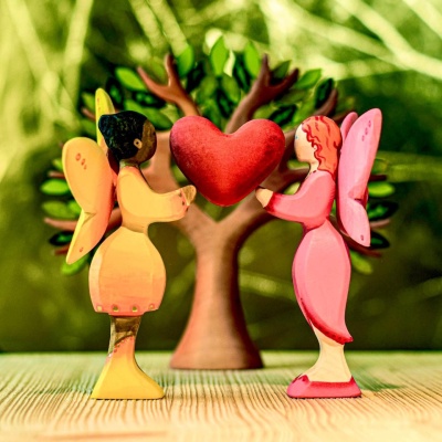 Two wooden Blossom Fairies holding a heart in front of a tree, handcrafted by Bumbu Toys