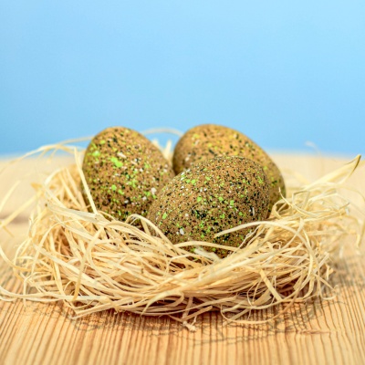 Three handcrafted wooden Ankylosaurus eggs in a straw nest.