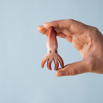 Hand holding a small handcrafted wooden squid