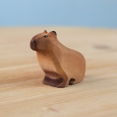 Handmade wooden capybara sitting on a wooden surface.