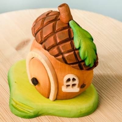 Child reaching for wooden bunny toys next to a fairy acorn house