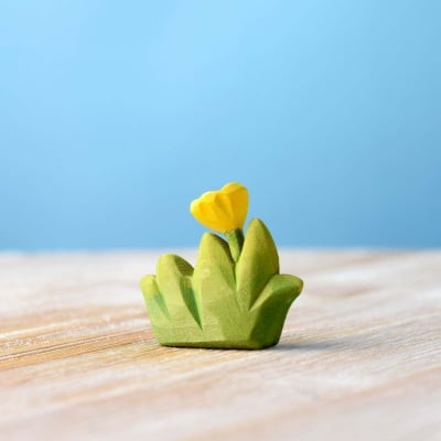 Sunny yellow flower wooden toy nestled in green grass by Bumbu Toys.