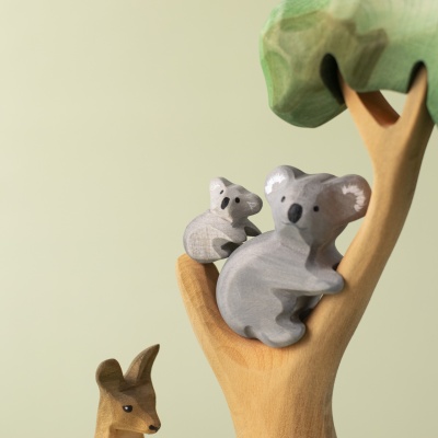 Koala cub placed on a tree branch with a parent koala figure.