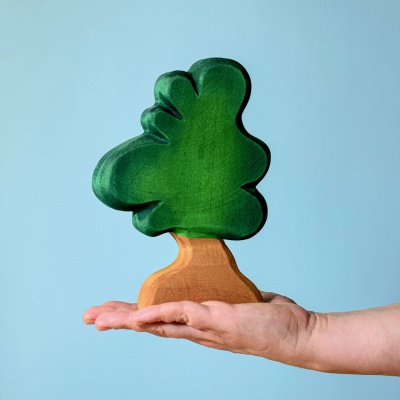 The wooden tree displayed on the floor of a child's playroom, dwarfing miniature wooden houses and animals.
