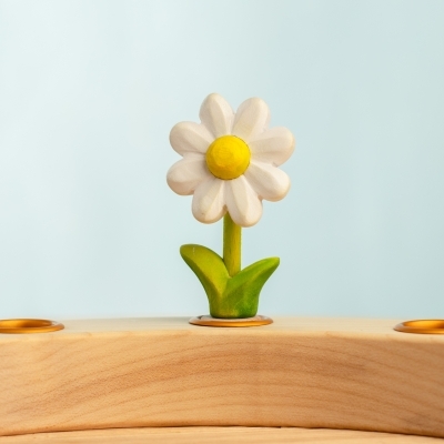Small wooden daisy toy standing on a curved wooden base