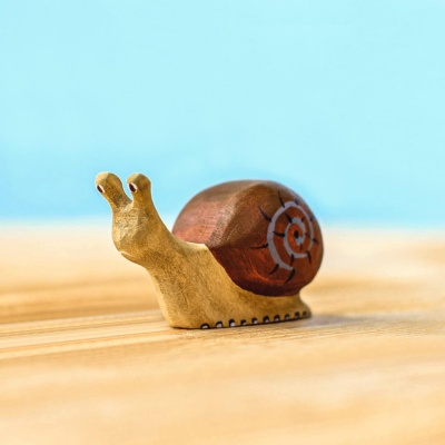 Hand-carved wooden snail toy on a wooden surface