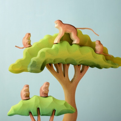 Monkeys playing in trees in a play scene with other wooden toys.