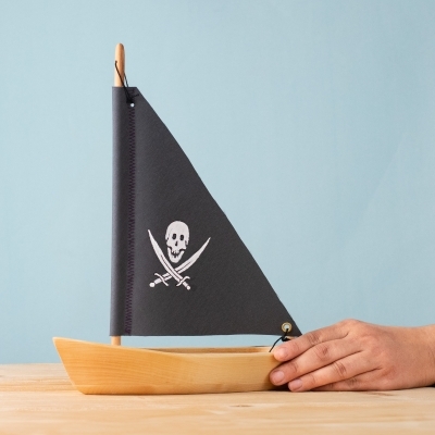 Wooden Pirate Sailing Boat with black sail held by hand for scale.