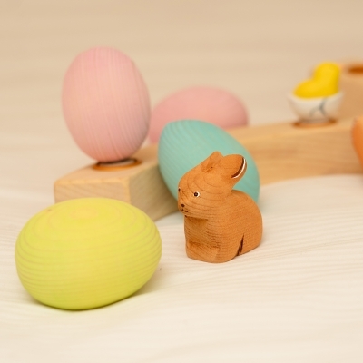 Small wooden fairy house surrounded by wooden bunnies and a pastel pink wooden Easter egg