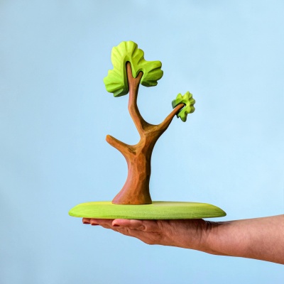 Wooden tree held in hand to show size