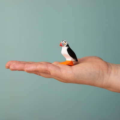dult hand holding a small wooden puffin toy to demonstrate its 4.5cm size.