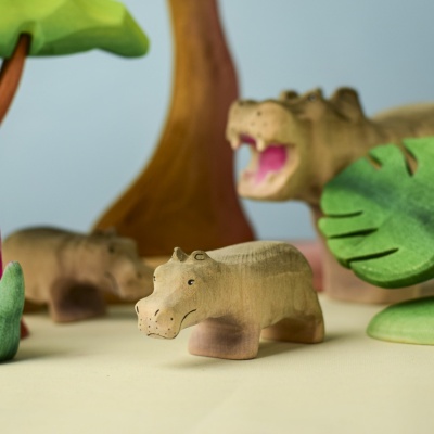 Two wooden Hippo Baby toys with background trees and plants.