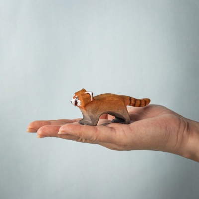 Red panda figure resting in a child’s hand