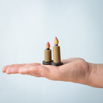 Two wooden candles from the Candles SET held in a hand, showing size variation.