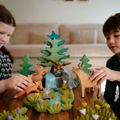 A child using the wooden stag toy to create a story alongside other animal figurines.