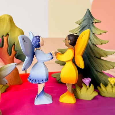 Two wooden fairies holding hands in a colorful nature scene, handmade by Bumbu Toys