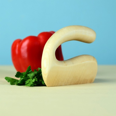 Child-friendly wooden chopper next to a red bell pepper