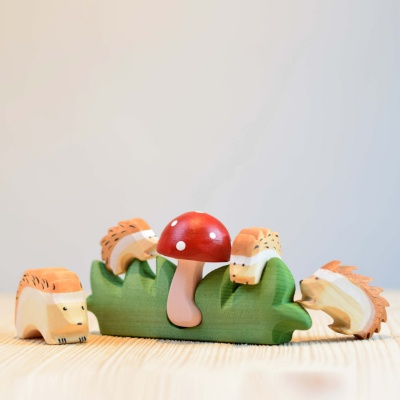 Image of the hedgehog nestled amongst other forest animal toys in a nature-themed play scene.