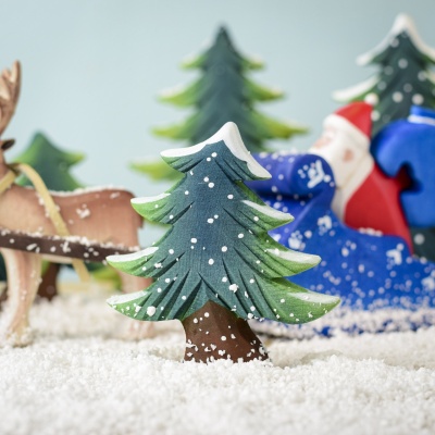 Snowy fir tree in a winter play scene with Santa and reindeer.
