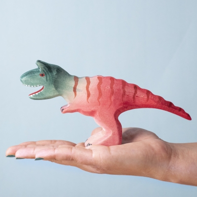 Adult Carnotaurus figure shown in hand for scale.