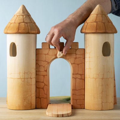 Hand showing how to open the wooden castle gate for play.